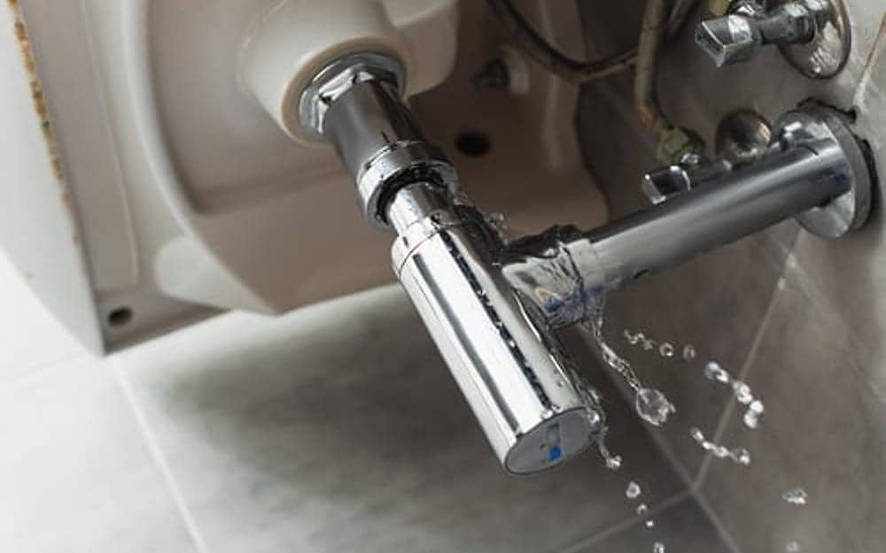 Close-up of a leaking chrome faucet dripping water in a residential bathroom