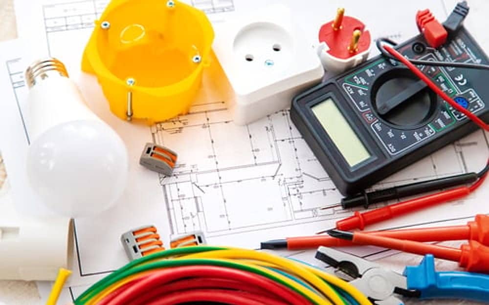 Multimeter, wiring and light bulbs laid out for residential electrical testing
