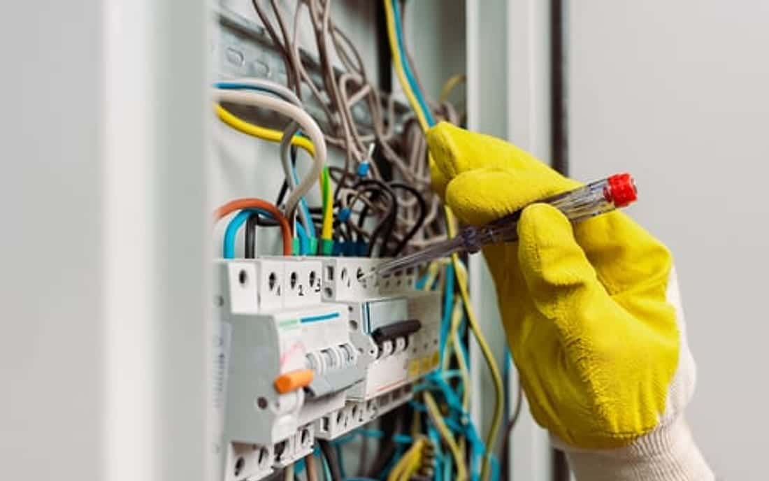 Technician in safety gloves working on a residential electrical panel for SoHo Home Multiservices