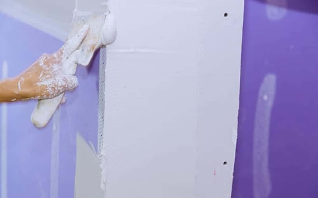 Drywall specialist smoothing joint compound over a wall seam during a SoHo Home Multiservices repair