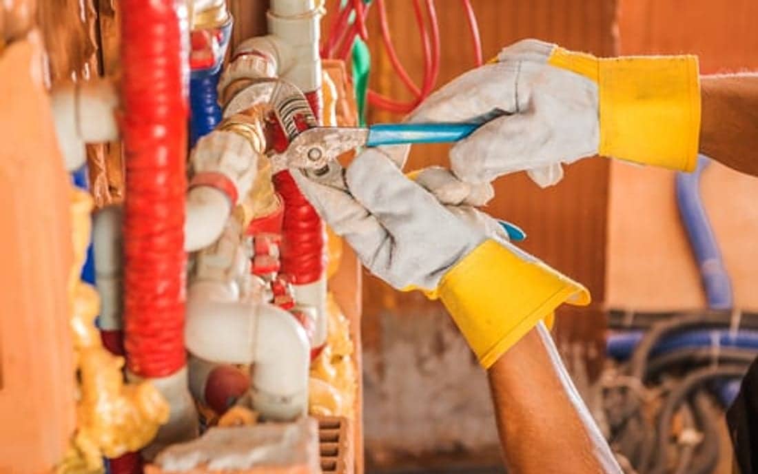Plumber in gloves connecting residential water supply lines on a SoHo Home Multiservices job